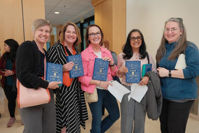 Happy attendees holding book titled "Lessons in Chemistry" by Bonnie Garmus