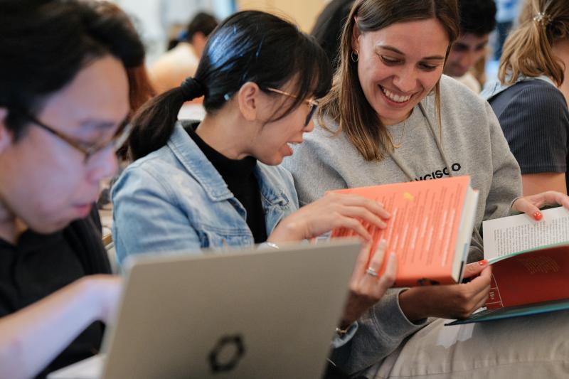 Two female attendees looking through Bonnie Garmus' book
